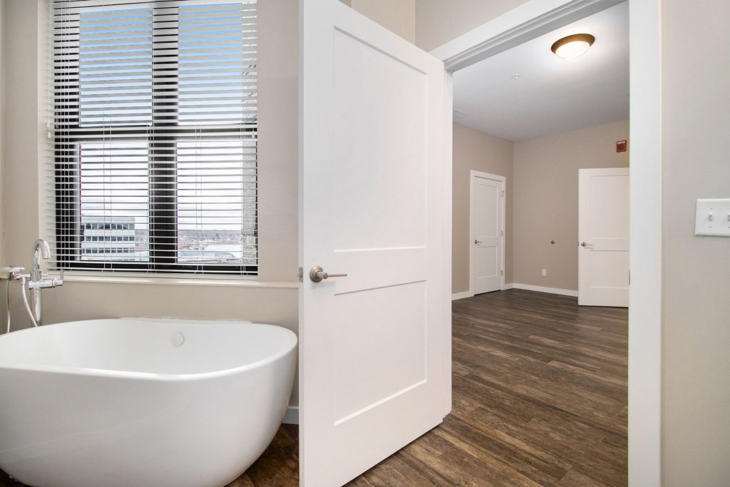 A white bathroom with a tub and a window.
