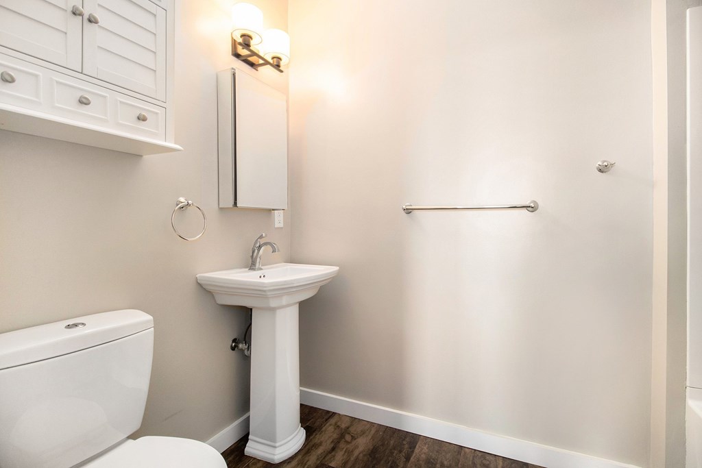 A white bathroom with a toilet, sink, and towel rack.