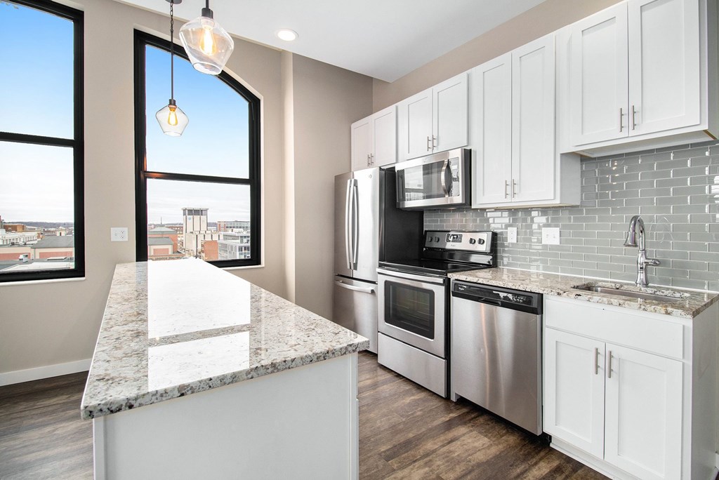 A kitchen with a marble countertop and stainless steel appliances.