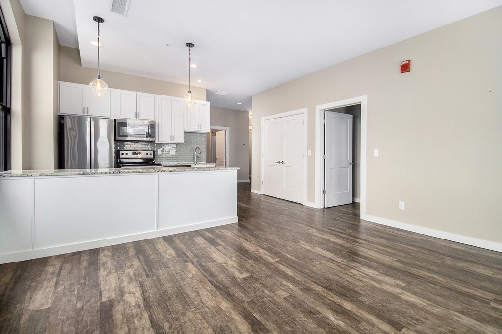 A kitchen with white cabinets and a wooden floor.
