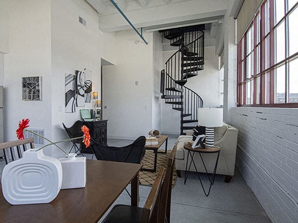 Steelcote Lofts dining/living room area with polished concrete floors, white exposed brick walls and black spiral staircase at Steelcote Square, St. Louis, MO