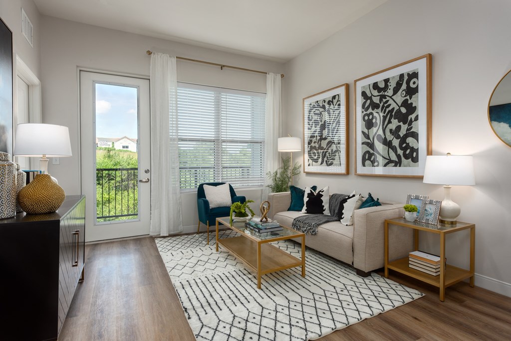 Modern living room with a couch coffee table, large window a door leading to a balcony  at Chapter at the Streets of St Charles, Saint Charles, MO