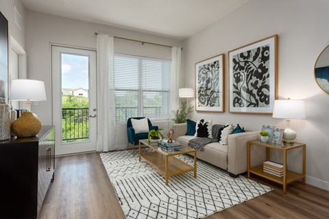 Modern living room with a couch coffee table, large window a door leading to a balcony  at Chapter at the Streets of St Charles, Saint Charles, MO