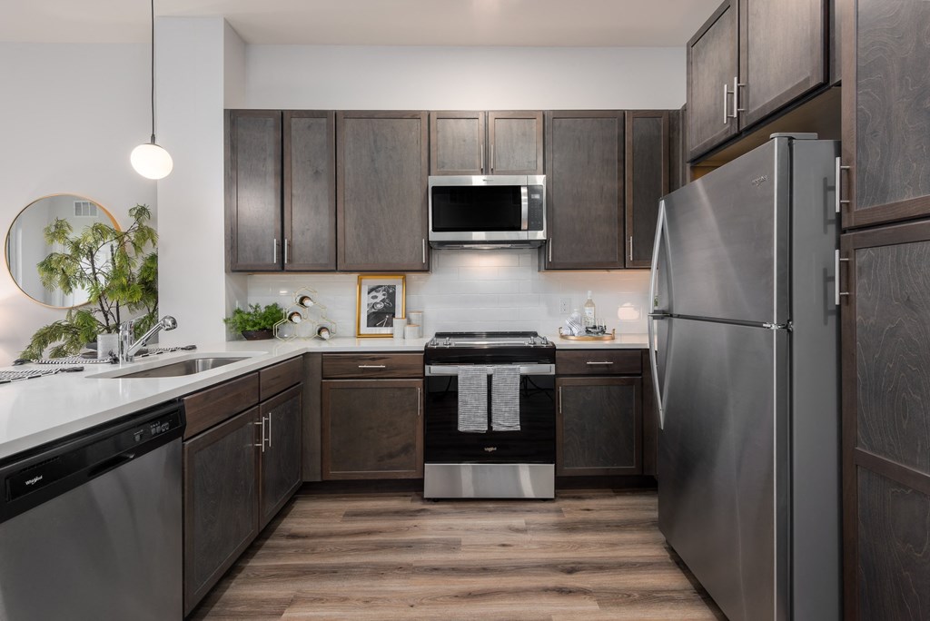 Modern kitchen with designer lighting, quartz countertops, dark cabinetry and stainless steel appliances  at Chapter at the Streets of St Charles, Saint Charles, MO