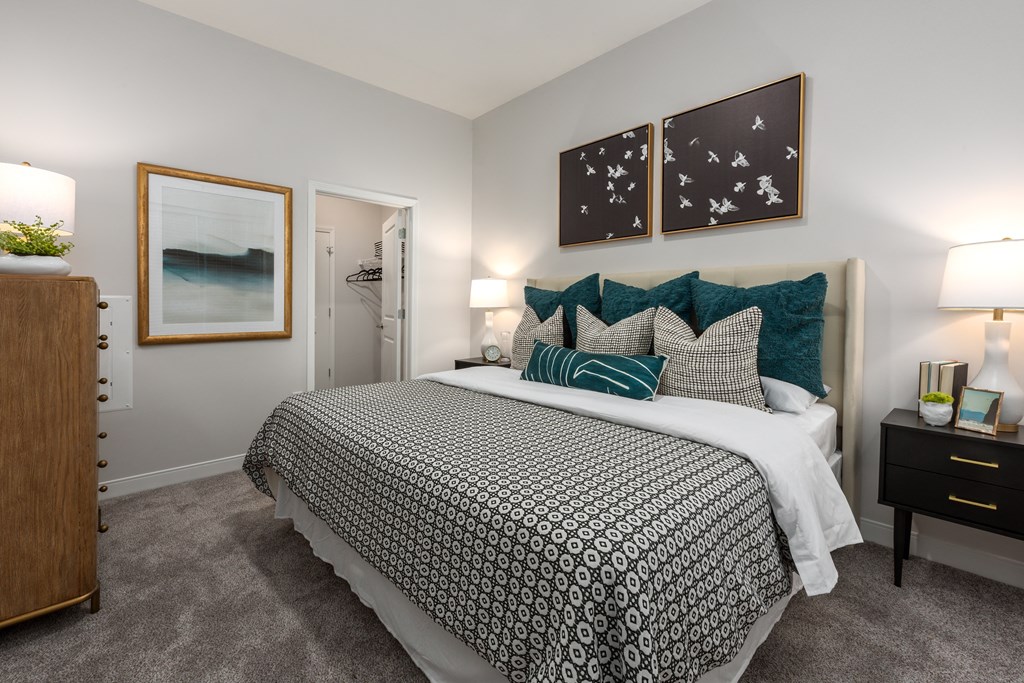 Modern bedroom with large bed, night stand, dresser and door leading to walk-in closet  at Chapter at the Streets of St Charles, Saint Charles, MO, 63303