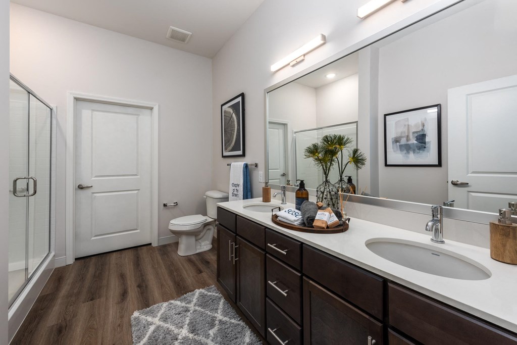 Modern bathroom with double vanity with granite countertops, dark cabinetry, designer lighting and walk in shower  at Chapter at the Streets of St Charles, Saint Charles, MO