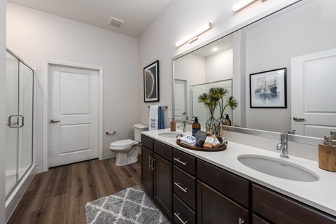 Modern bathroom with double vanity with granite countertops, dark cabinetry, designer lighting and walk in shower  at Chapter at the Streets of St Charles, Saint Charles, MO