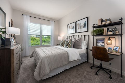 Modern bedroom with large window, bed, dresser and small work station  at Chapter at the Streets of St Charles, Saint Charles, MO, 63303