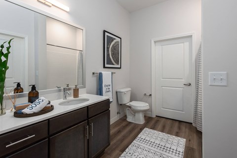 Modern bathroom with double vanity with granite countertops, dark cabinetry, designer lighting and walk in shower at Chapter at the Streets of St Charles, Missouri, 63303