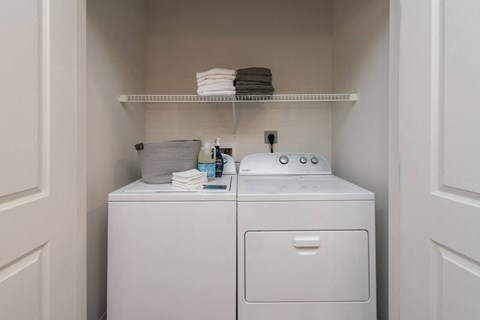Full-size washer and dryer in unit with wire shelf above  at Chapter at the Streets of St Charles, Missouri