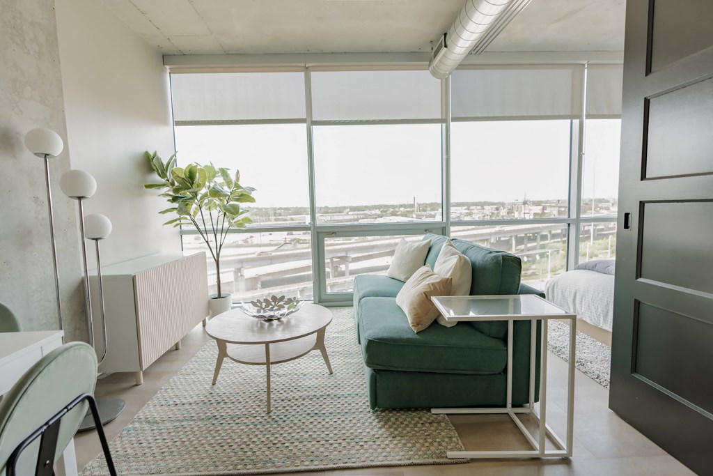 a living room with a green couch and a table    and a window at One Foundry Way, St. Louis, Missouri