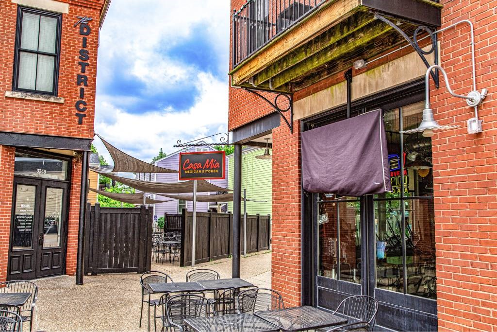 A patio area with tables and chairs outside a building with a sign that says "District".