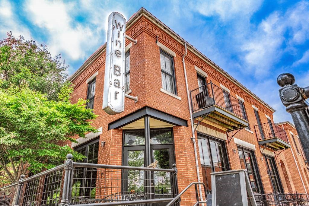 A red brick building with a white sign that says "Wine Bar".