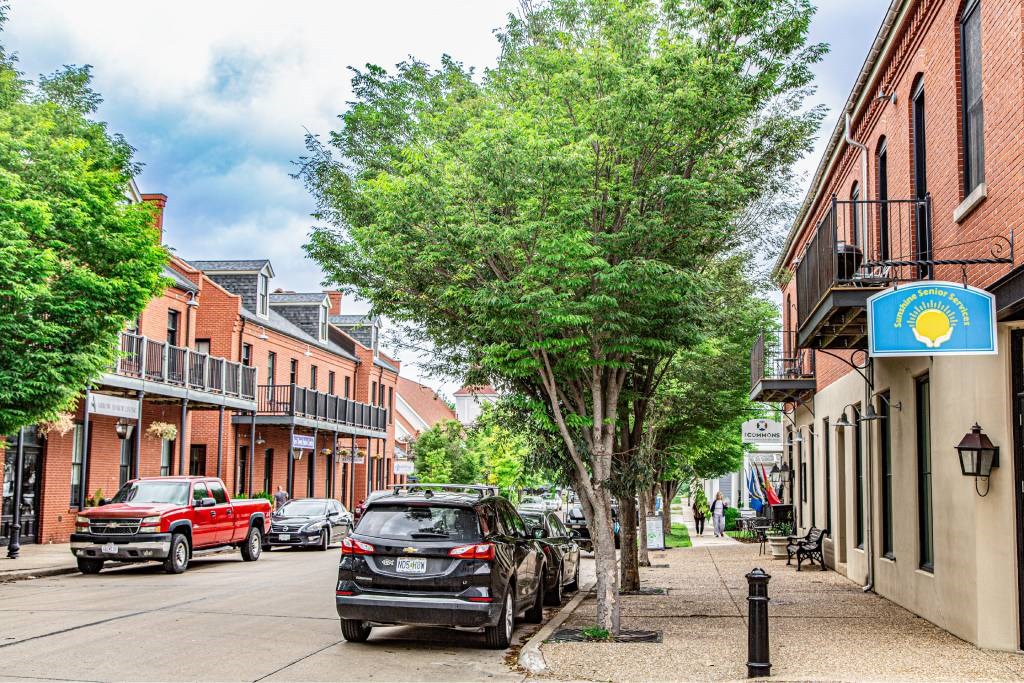 A street view with cars and a blue sign with a sun on it.