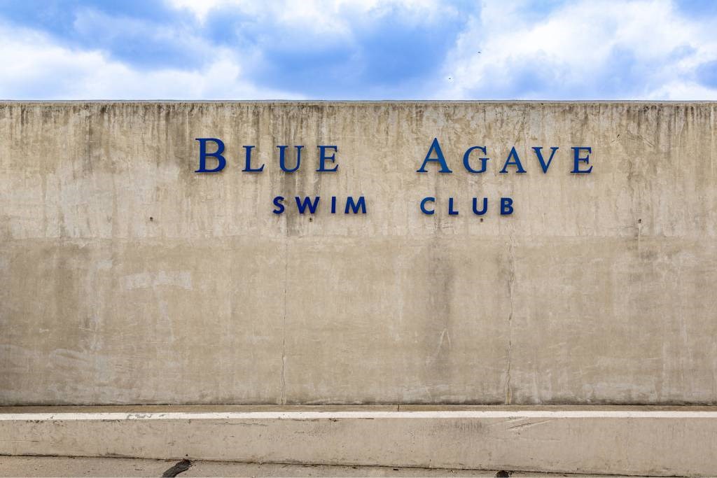 A wall with the words Blue Agave Swim Club written on it.
