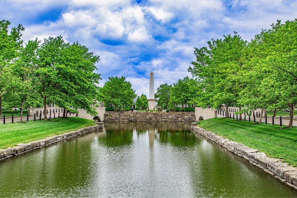 A serene landscape with a water body, trees, and a monument in the background.