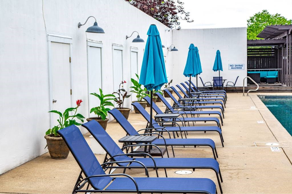 A poolside area with blue lounge chairs and umbrellas.