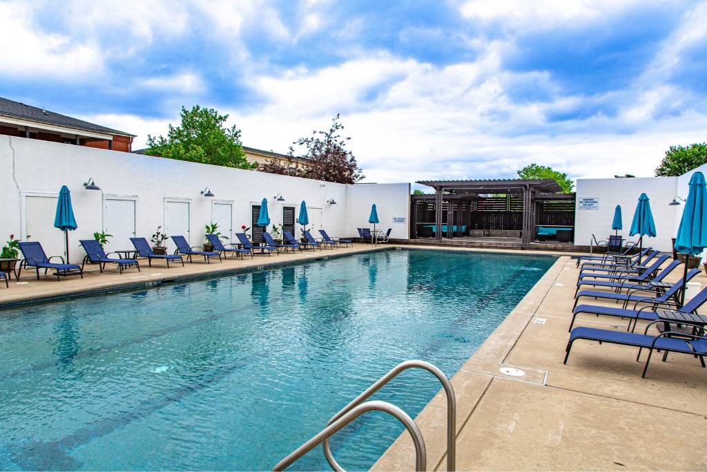 A pool with blue umbrellas and chairs.