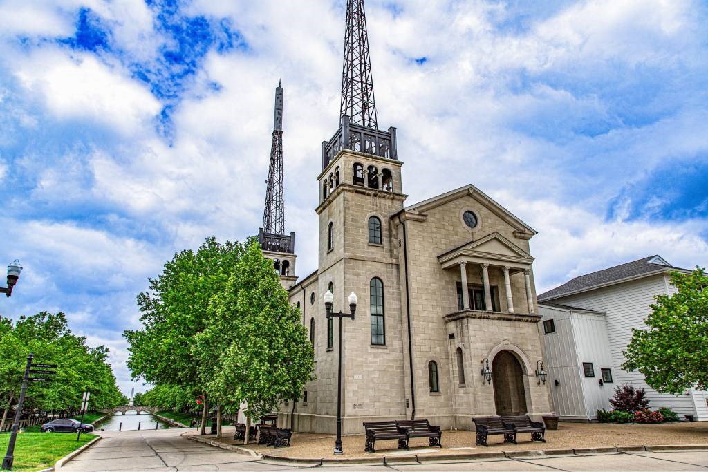 A church with a tall steeple and a clock tower stands in front of a white building.