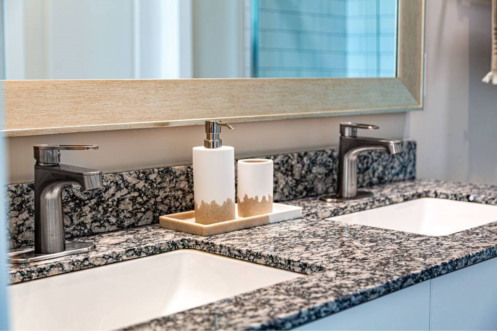 A bathroom counter with two sinks and a soap holder.