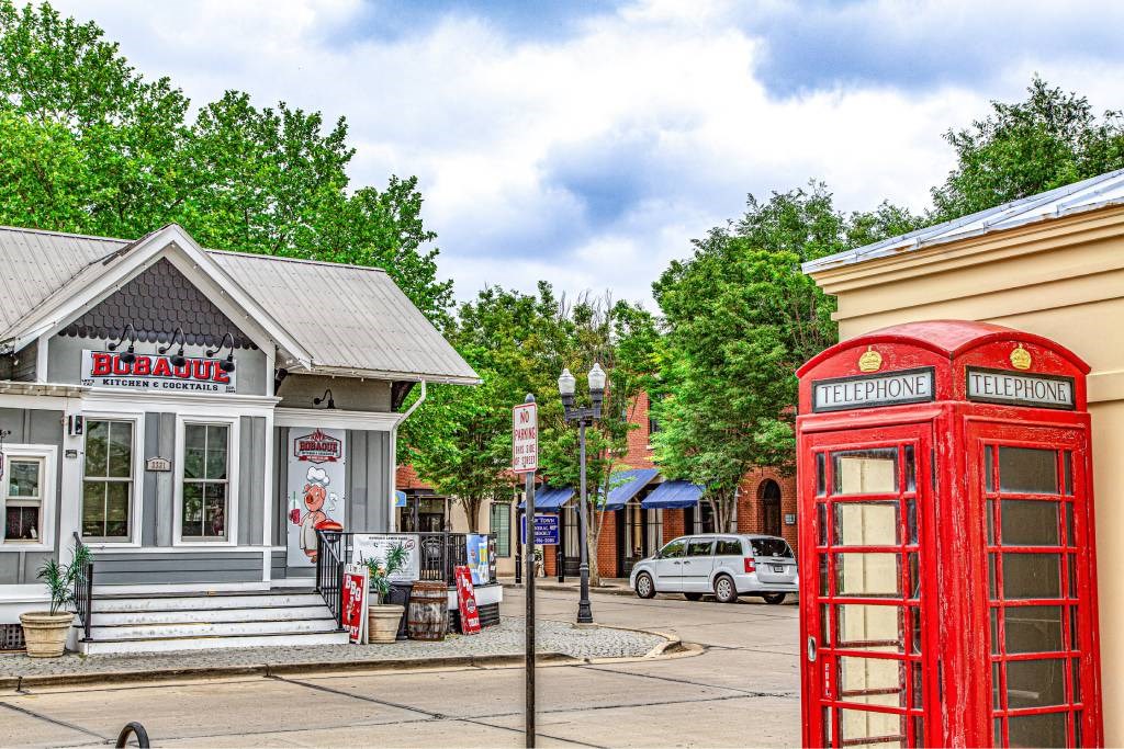 A red telephone booth stands next to a building with a sign that says "Bubba's Barbecue.".