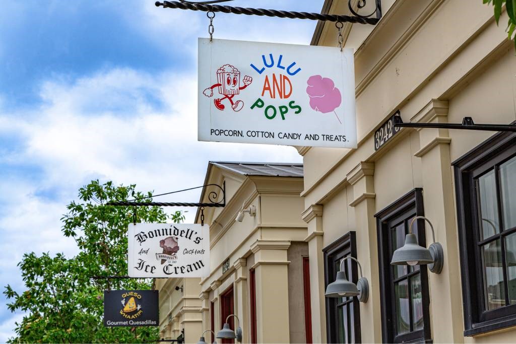 A sign for popcorn, cotton candy, and treats hangs above a building.