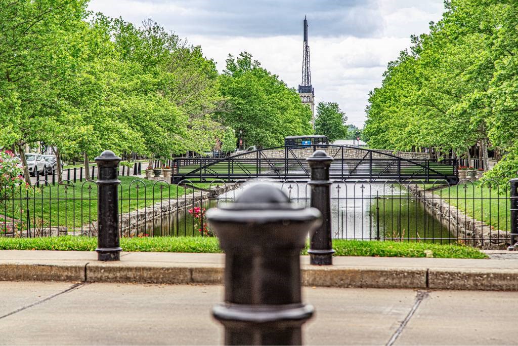 A black metal fence surrounds a green park area.