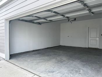 A garage with a white door and a concrete floor.