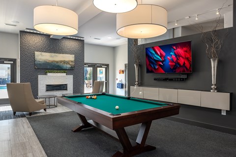 A room with a pool table and a television mounted on the wall.