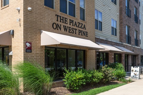 The Plazza on West Pine is a multi-story building with a beige facade and a white awning.