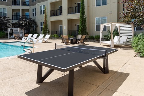 A black table tennis table is in the middle of a concrete patio.