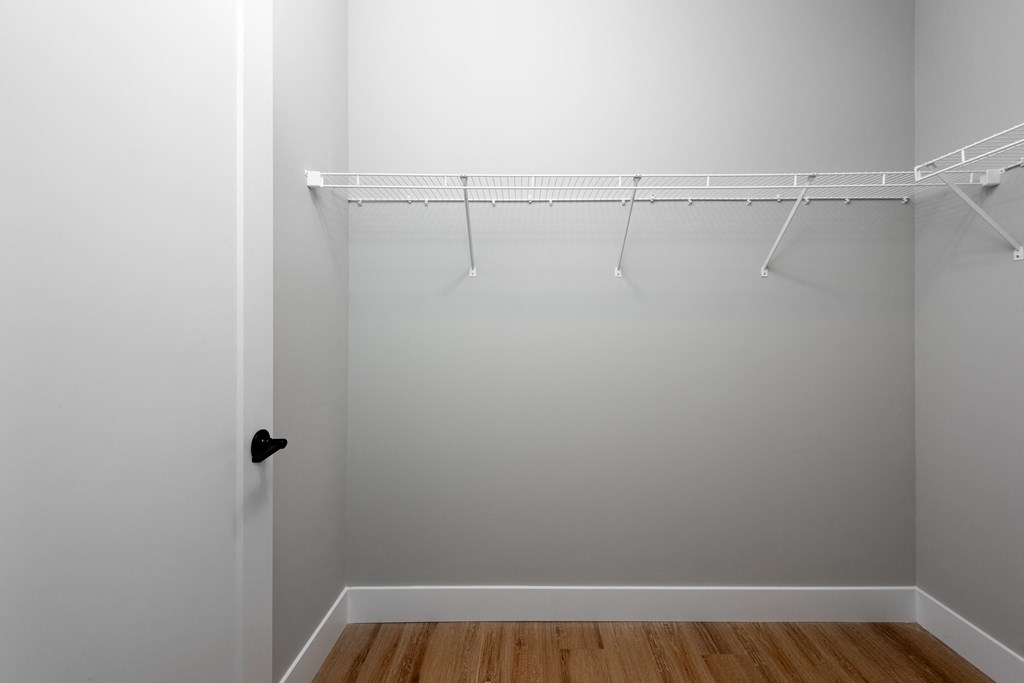 an empty closet with white walls and wooden floors