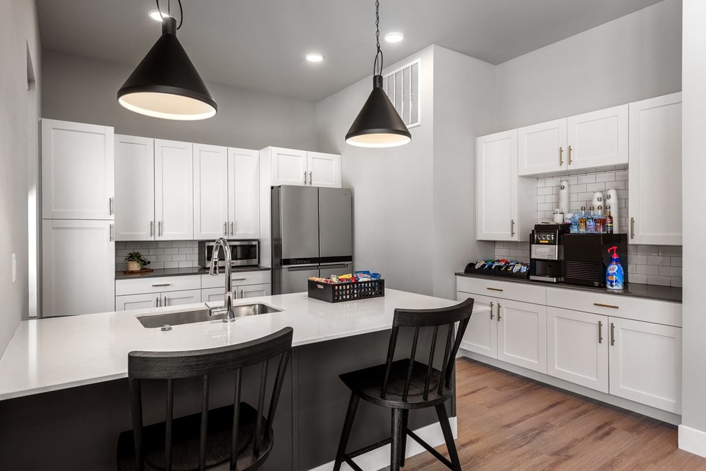 a kitchen with white cabinets and a large island with two chairs