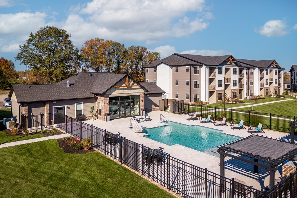 an outdoor pool with lounge chairs in front of an apartment building