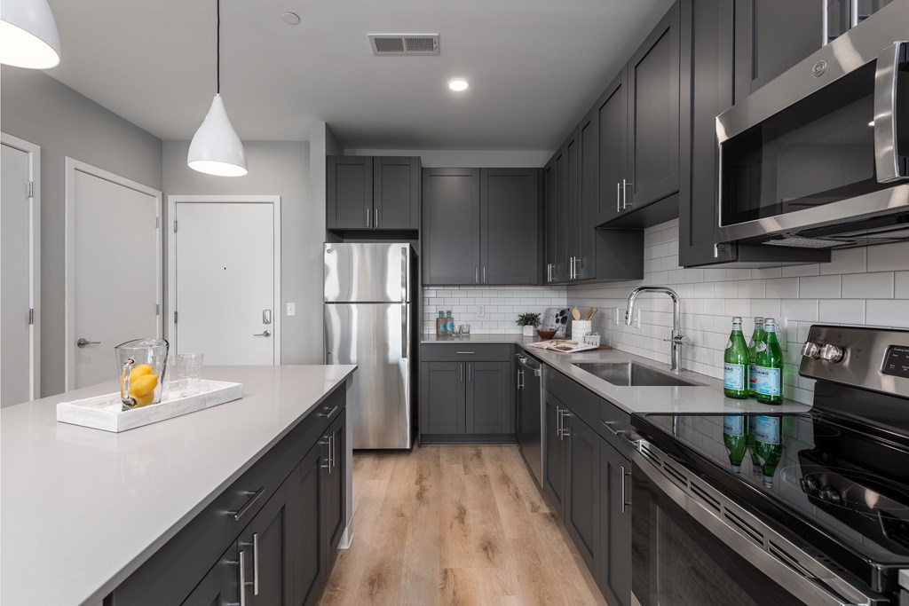 a kitchen with black cabinets and white counter tops and a stainless steel refrigerator a kitchen with black cabinets and white counter tops and a stainless steel refrigerator at The Edwin on Grand Apartments, St Louis