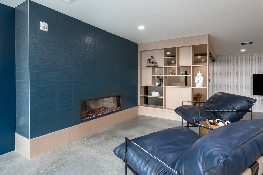 a living room with blue couches and a fireplace at The Edwin on Grand Apartments, St Louis, MO, 63103