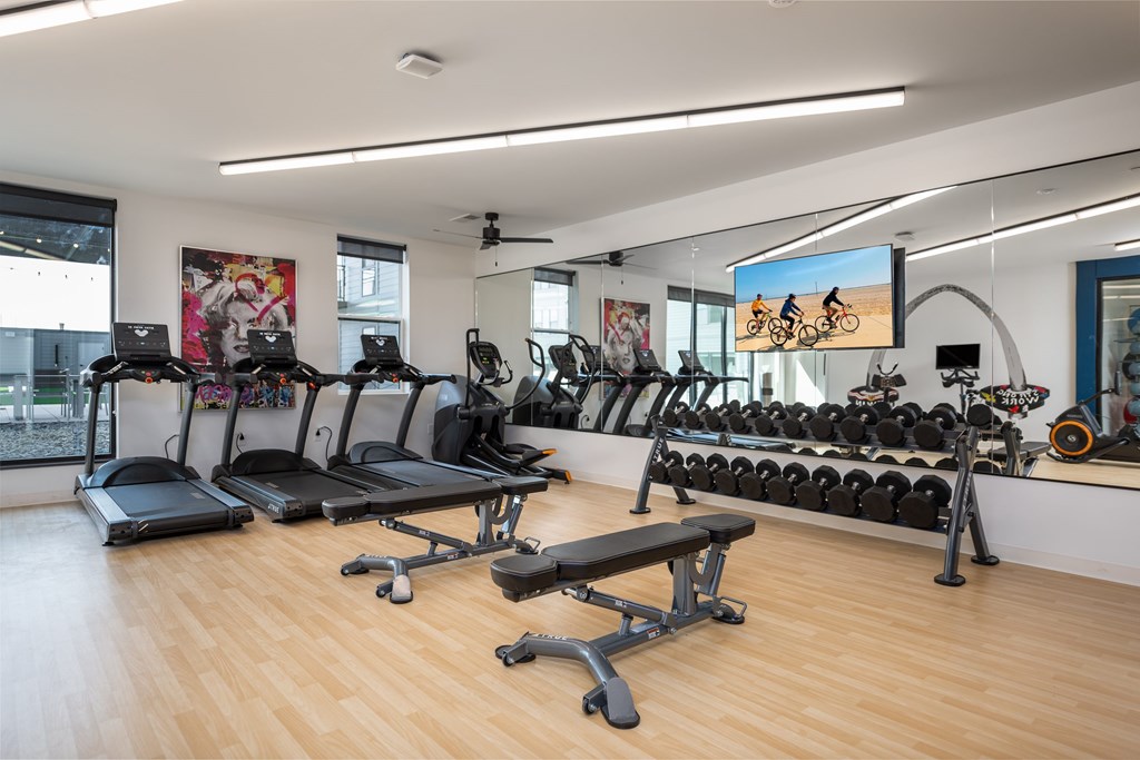 a gym with cardio equipment and mirrors on the wall a gym with cardio equipment and mirrors on the wall at The Edwin on Grand Apartments, St Louis