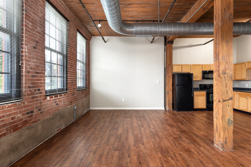 an empty living room with a brick wall and wood floors at Lofts at Lafayette Square Apartments, Missouri, 63104