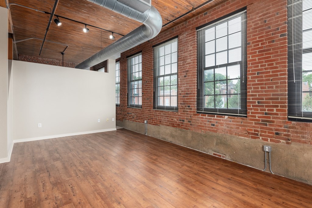 an empty living room with brick walls and wood floor at Lofts at Lafayette Square Apartments, Missouri