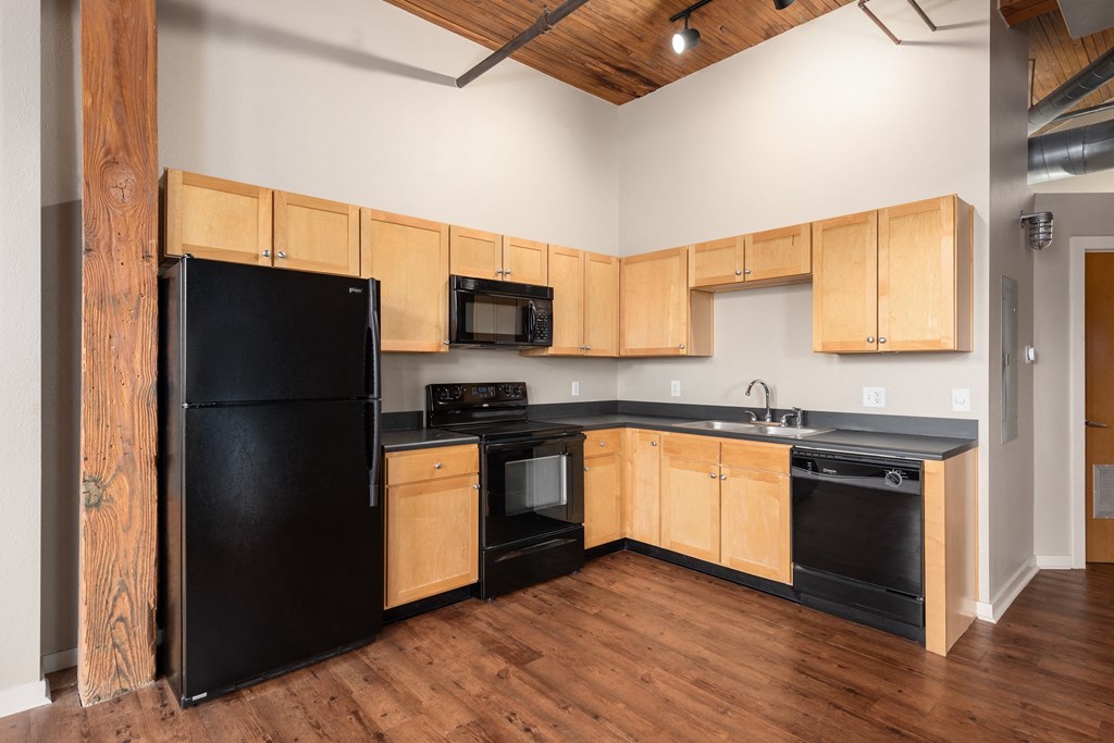 A kitchen with black appliances and wooden cabinets at Lofts at Lafayette Square Apartments, Saint Louis