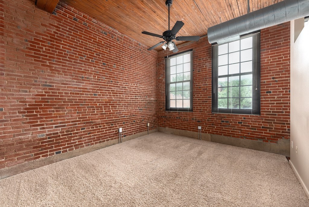 an empty room with a brick wall and a ceiling fan at Lofts at Lafayette Square Apartments, Saint Louis, Missouri