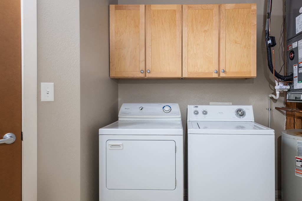 A white dryer and washer are sitting next to each other in a small laundry room at Lofts at Lafayette Square Apartments, Saint Louis, MO, 63104