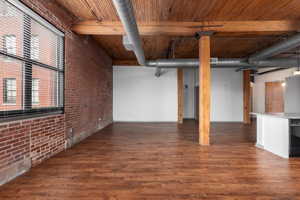 A room with wooden floors and a brick wall with a window at Lofts at Lafayette Square Apartments, Missouri, 63104