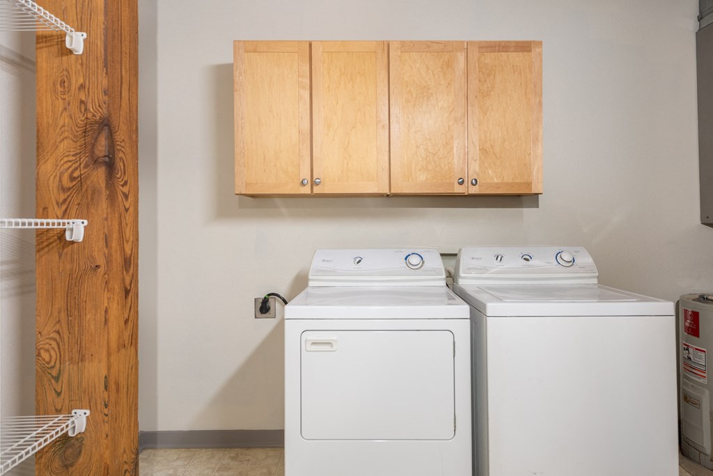 a washer and dryer in a laundry room with wooden cabinets at Lofts at Lafayette Square Apartments, Saint Louis