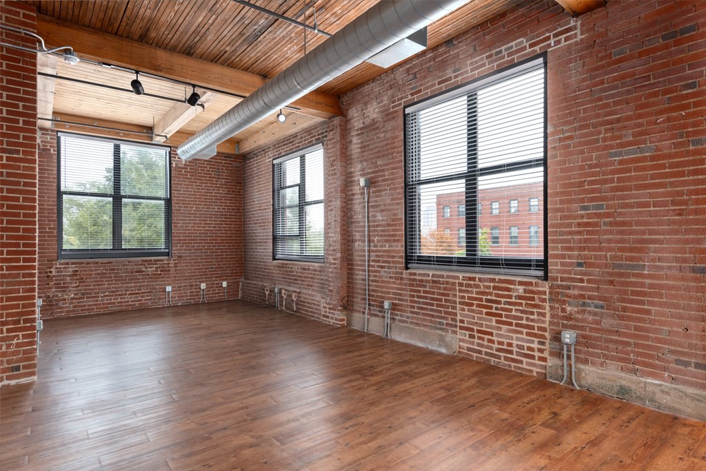 an empty living room with brick walls and wood floors at Lofts at Lafayette Square Apartments, Missouri