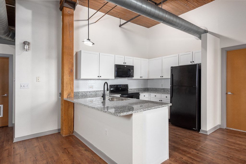 a kitchen with an island and a black refrigerator at Lofts at Lafayette Square Apartments, Saint Louis