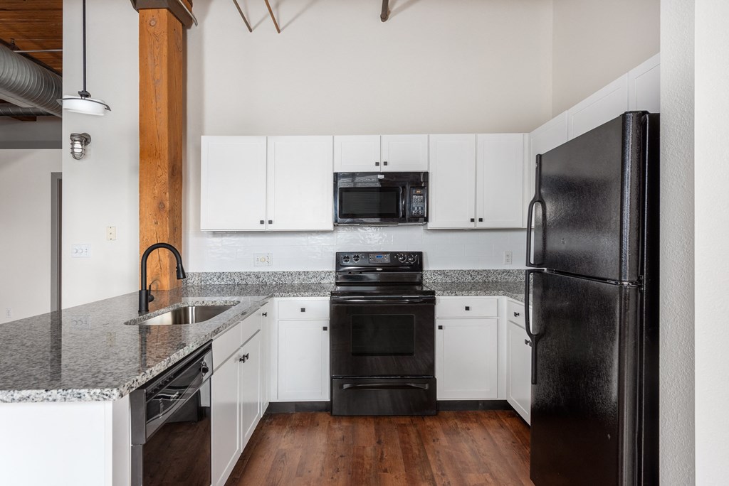 a kitchen with white cabinets and black appliances and granite counter tops at Lofts at Lafayette Square Apartments, Saint Louis, Missouri