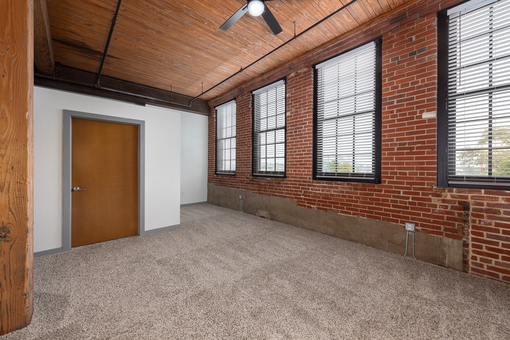 the interior of an empty room with brick walls and a door at Lofts at Lafayette Square Apartments, Saint Louis, MO