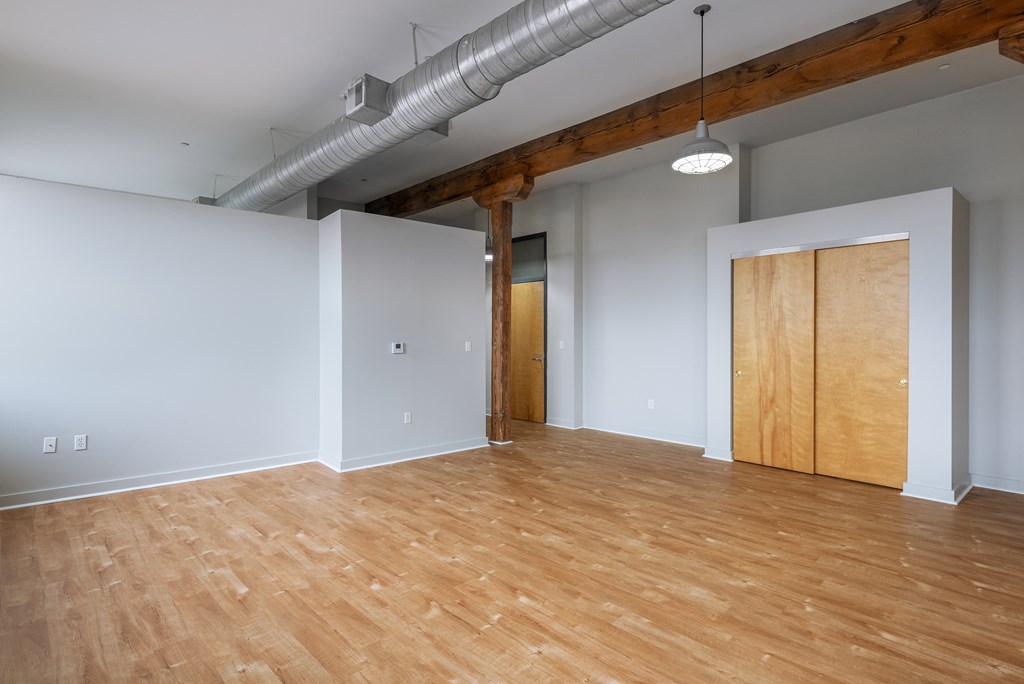 an empty living room with wood floors and a door to a closet at Lofts at Lafayette Square Apartments, Saint Louis, Missouri