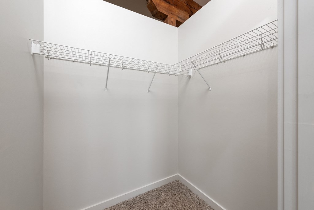 a spacious walk in closet in a bedroom with white walls and a ceiling with shelves at Lofts at Lafayette Square Apartments, Saint Louis, MO